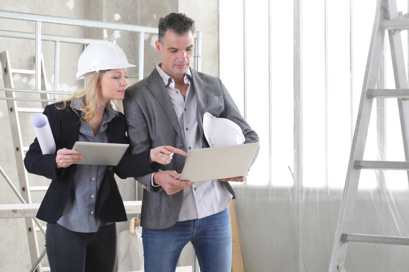 Technicians discussing a preventive maintenance checklist in a building undergoing renovation