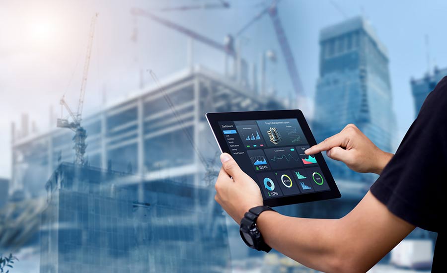 A construction manager with a laptop in front of a construction project