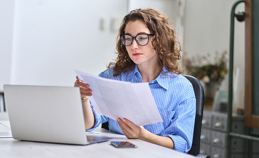 A young woman looking at documents in front of her computer​